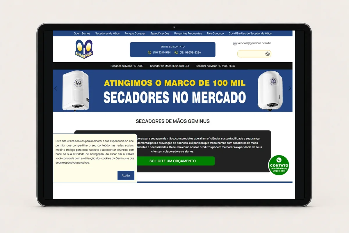 Site atual da Geminus apresentado em tablet, destacando secadores de mãos e solicitação de orçamento